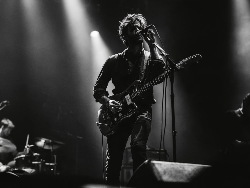 Guitar player singing into a mic with a floor monitor in front
